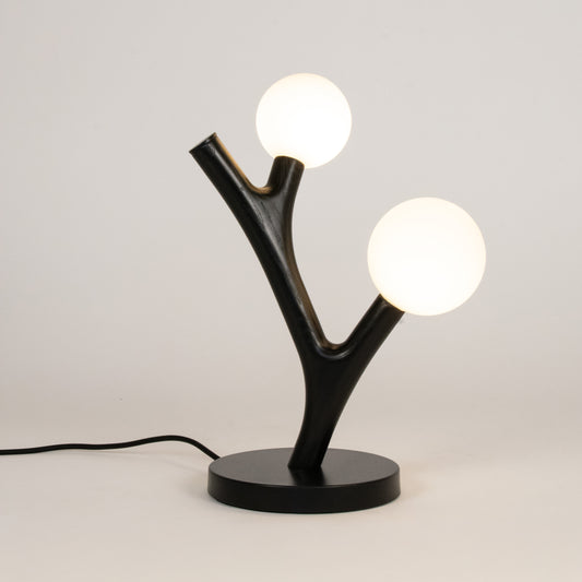 Modern table lamp with black base and branch-like design on a white background