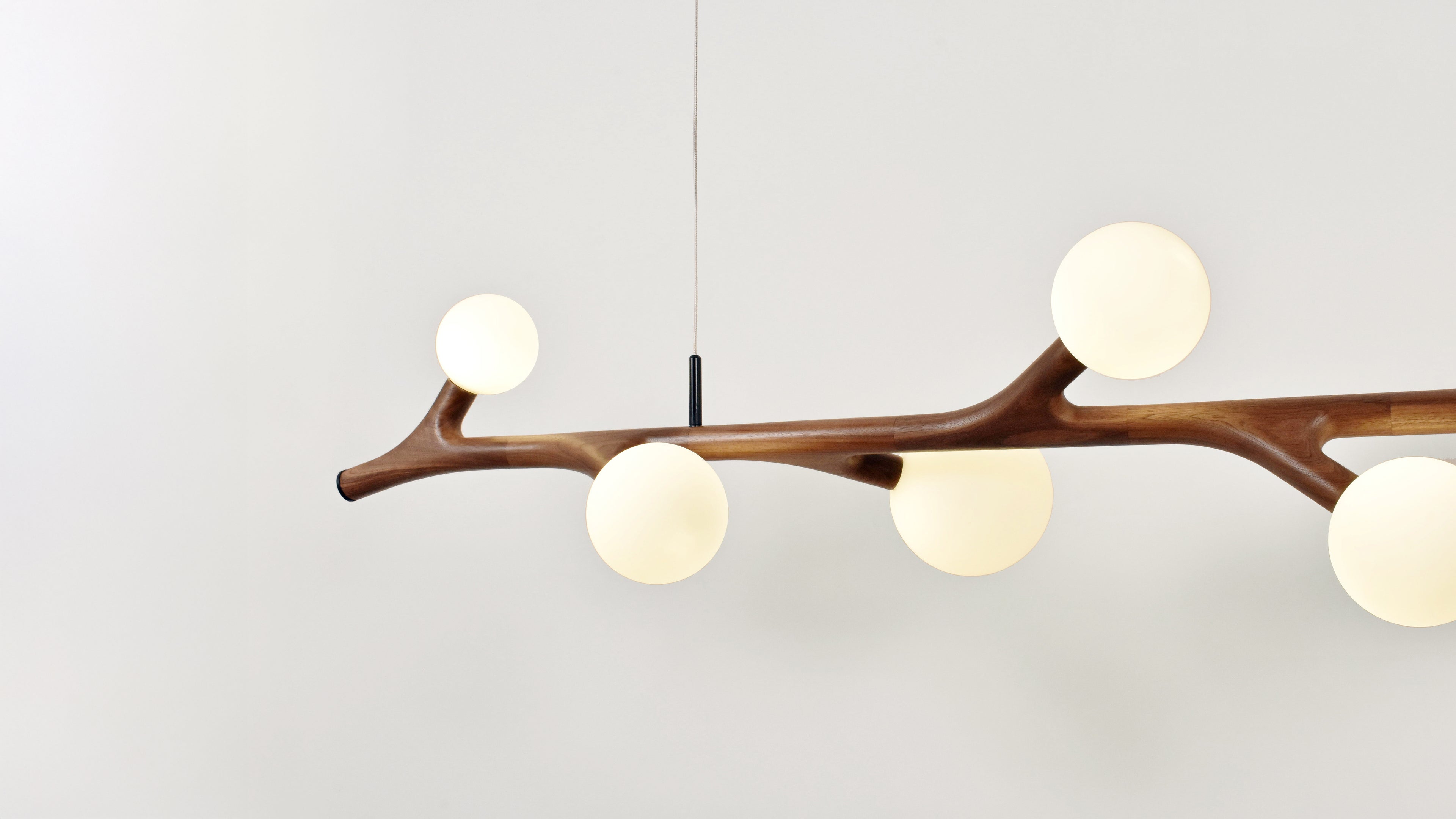 Modern Arborlux chandelier with branch-like design and round glass shades on a plain background