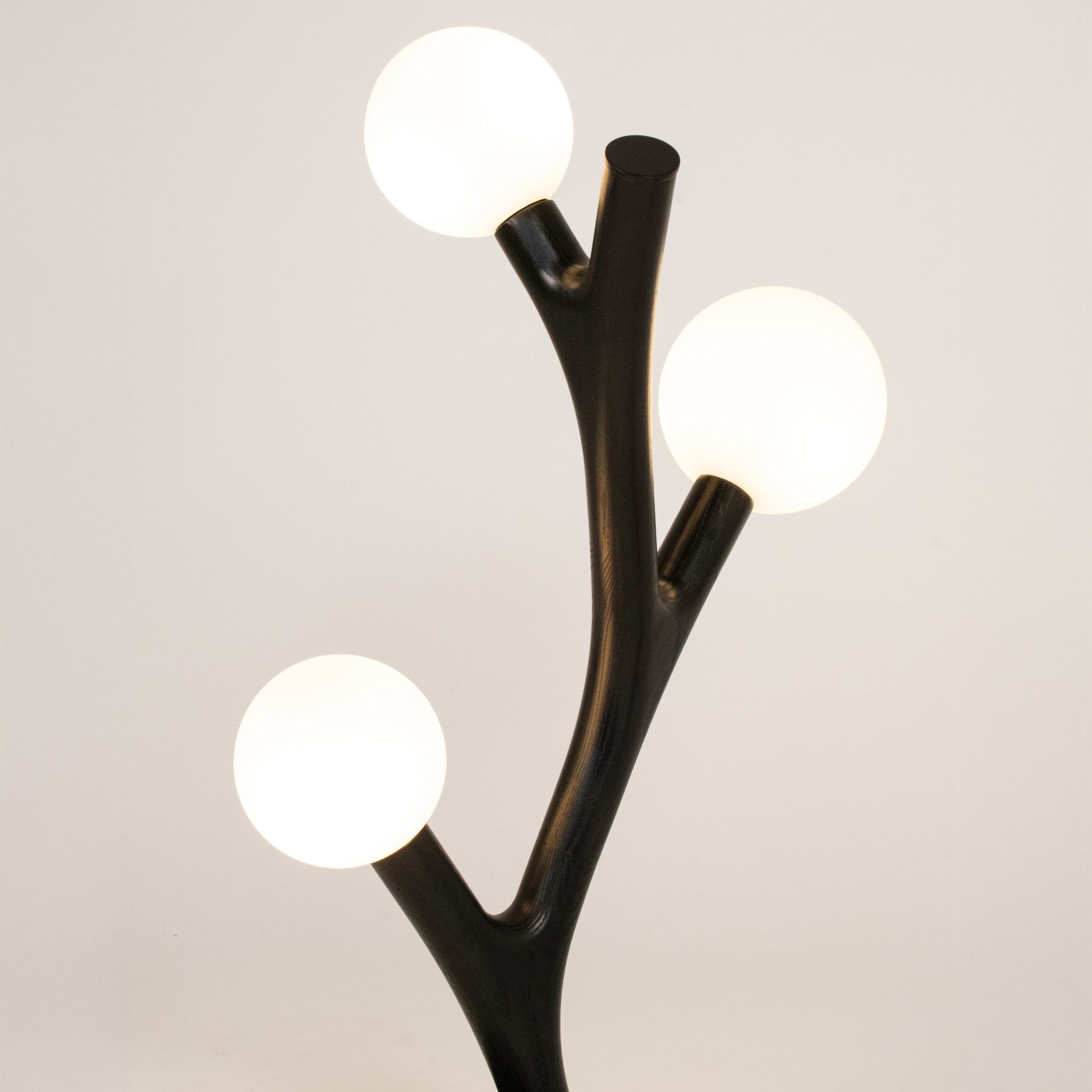 Modern black branch-style lamp with three round lights on a neutral background