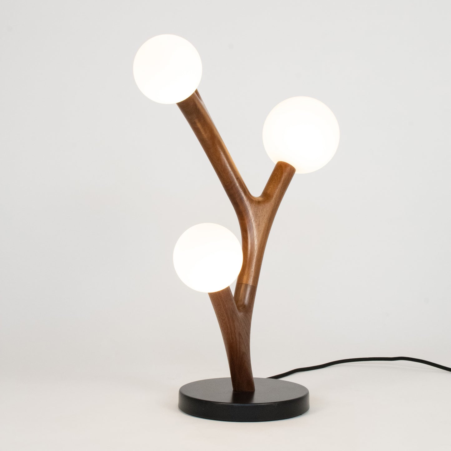 Table lamp with wooden branch design and three round lights on a white background