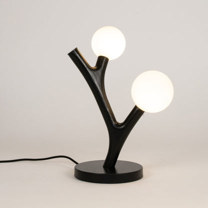 Modern table lamp with black base and branch-like design on a white background