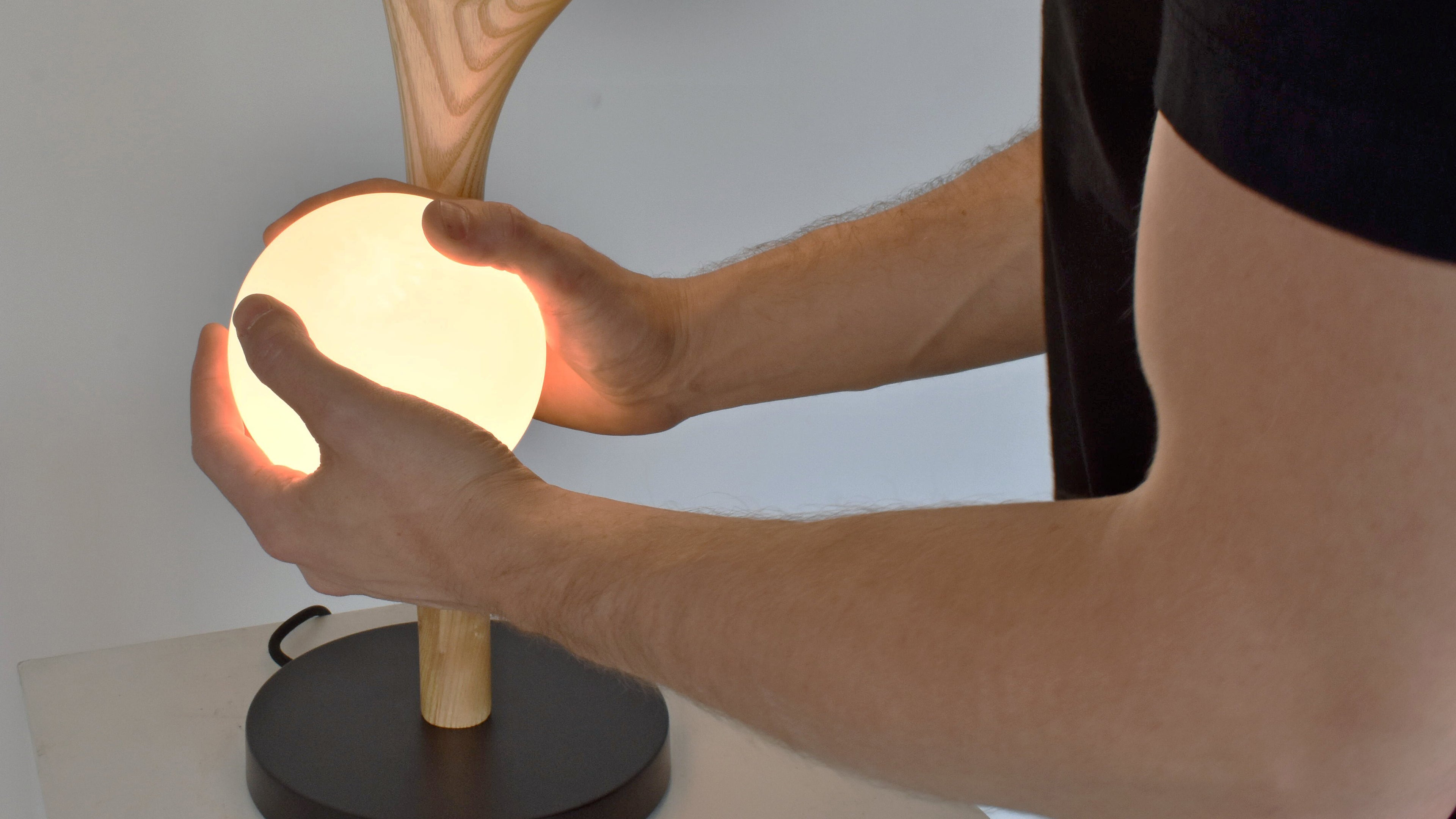Person holding a small lamp with wooden base and black base
