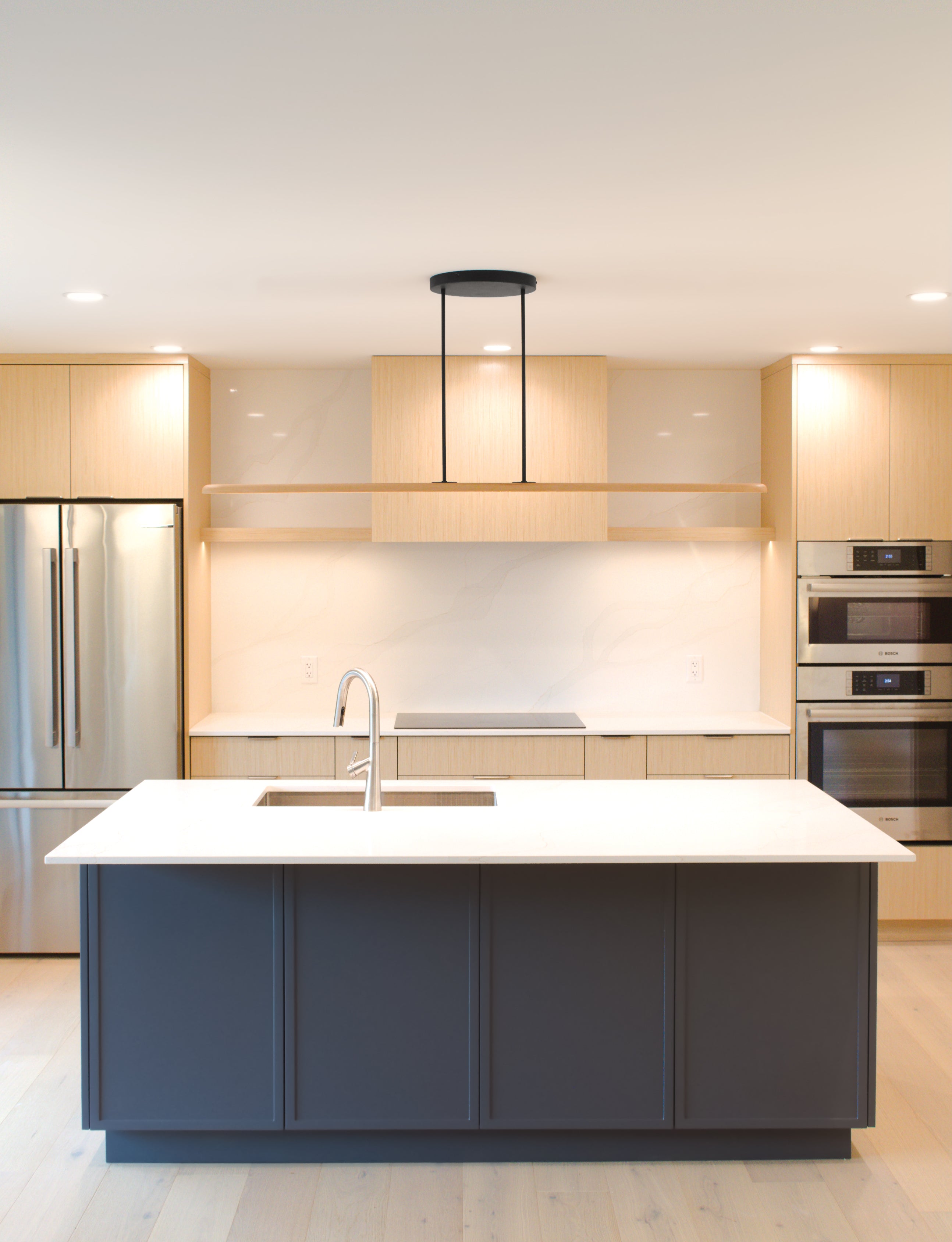 Nimbus solid hardwood linear pendant light hanging over blue kitchen island